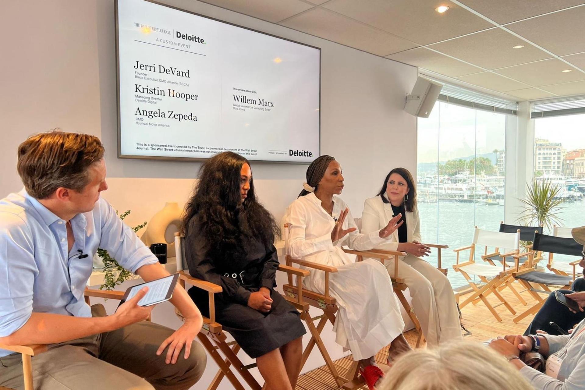 A mixed-gender panel seated in director’s chairs in a bright event space; a screen behind them lists the names Jerri DeVard (BECA), Kristin Hooper (Deloitte Digital), Angela Zepeda (Hyundai Motor America), and moderator Willem Marx.