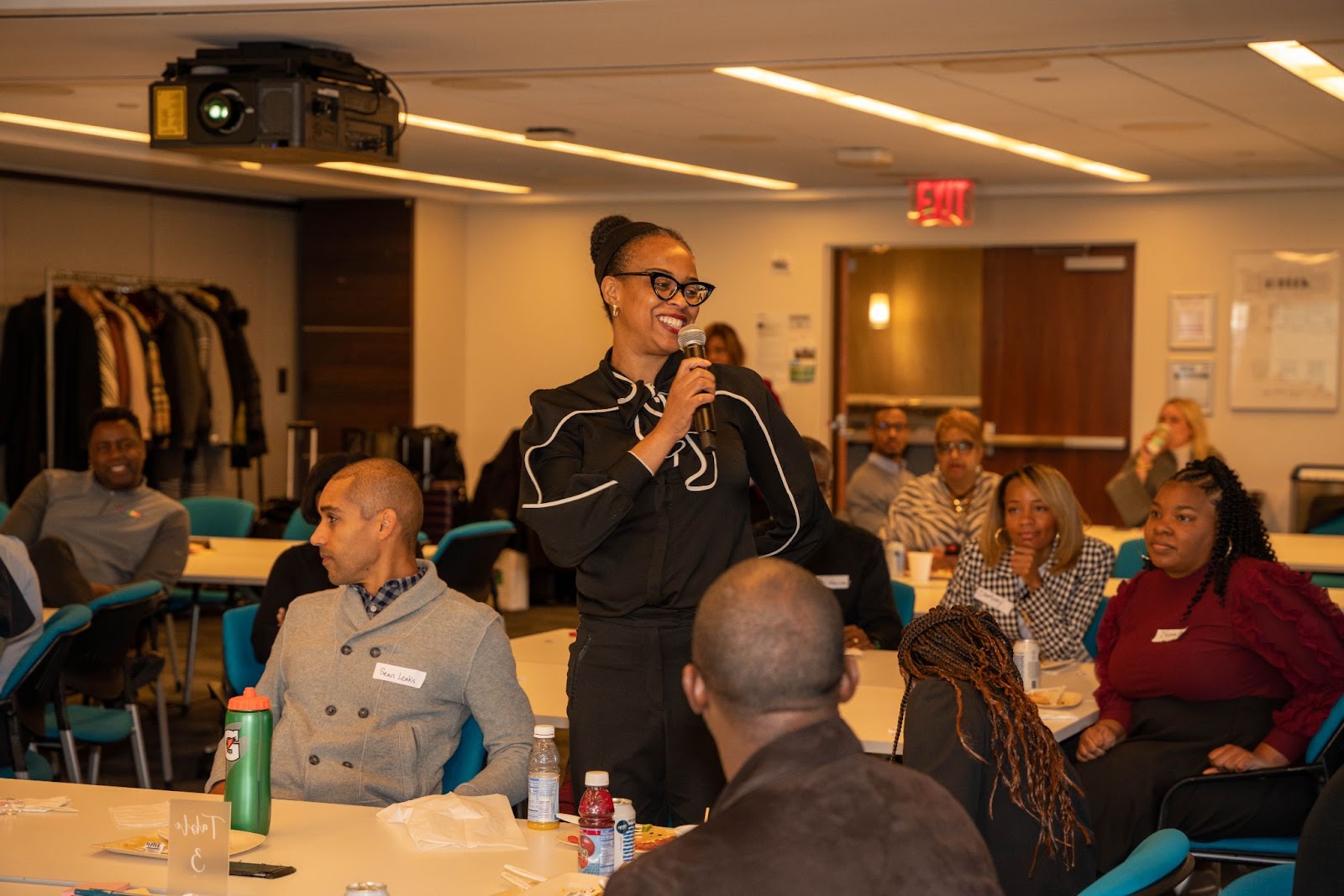 A woman enthusiastically addressing an audience with a microphone, creating a lively and engaging atmosphere in a conference setting.