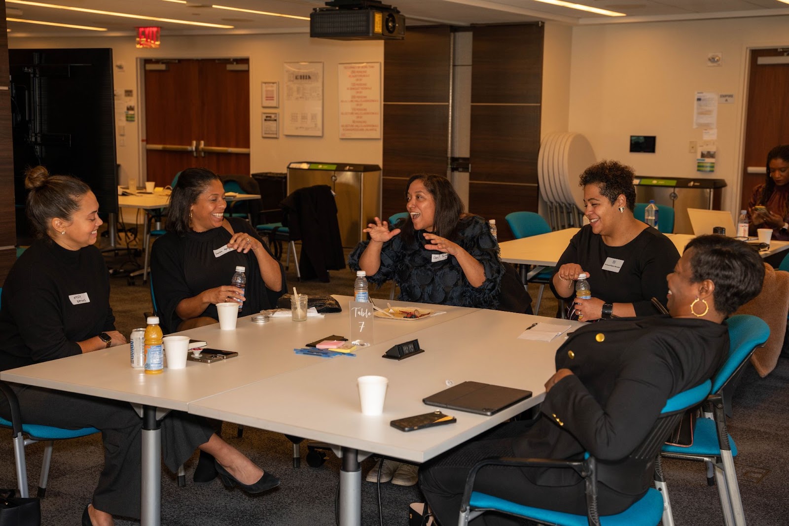 A group of women seated together at a table, laughing and engaging in a lively conversation during a networking event.