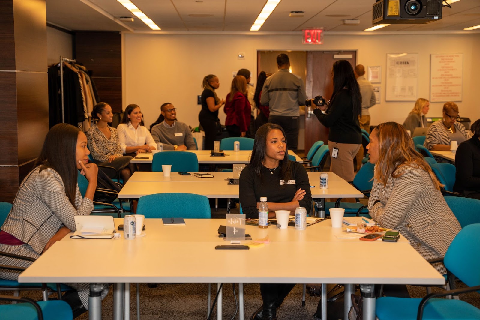 Participants engage in conversation at tables during a professional event in a well-lit conference room.