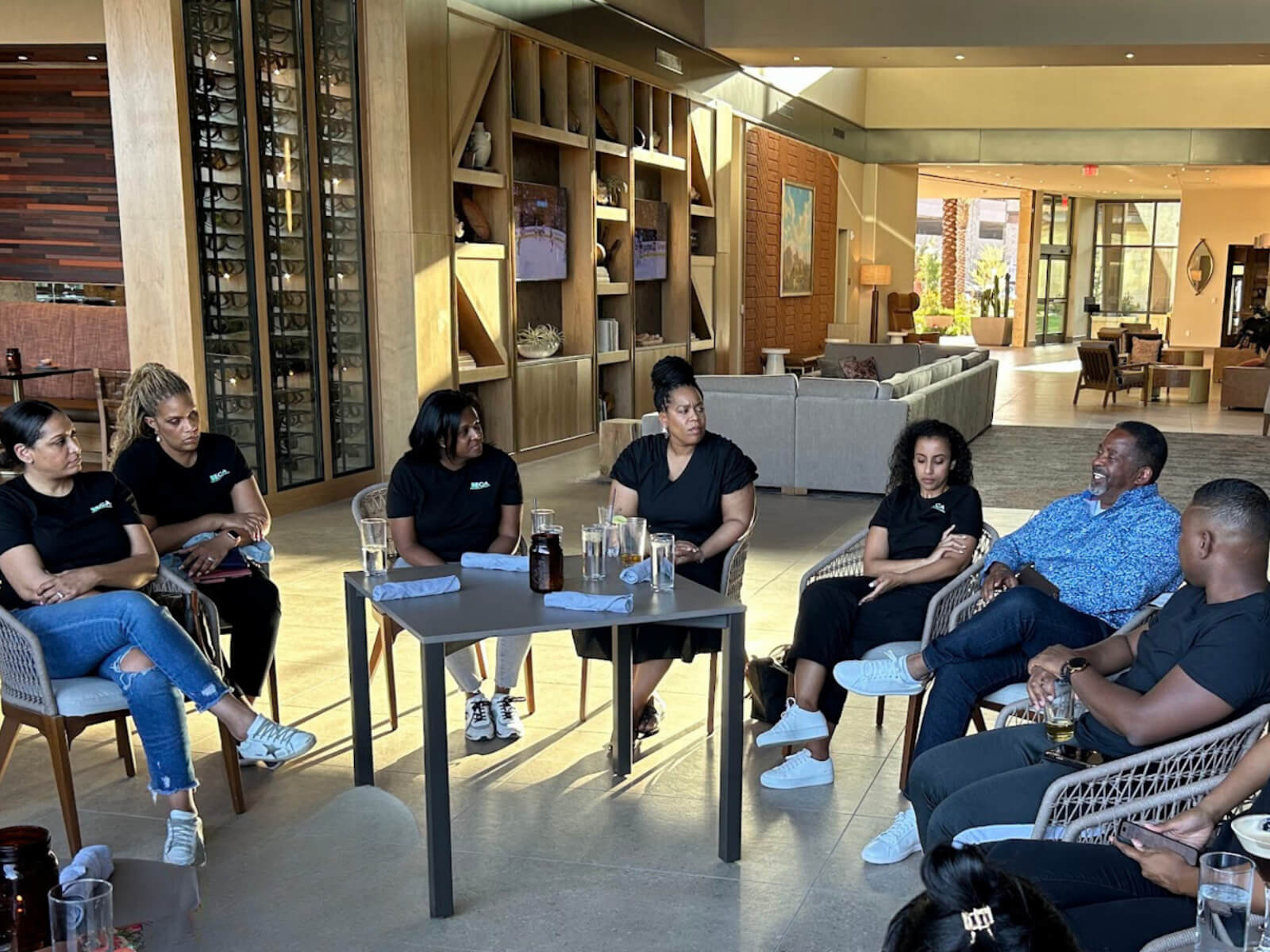 A group of people sitting in a circle in a modern indoor setting, participating in a thoughtful discussion.