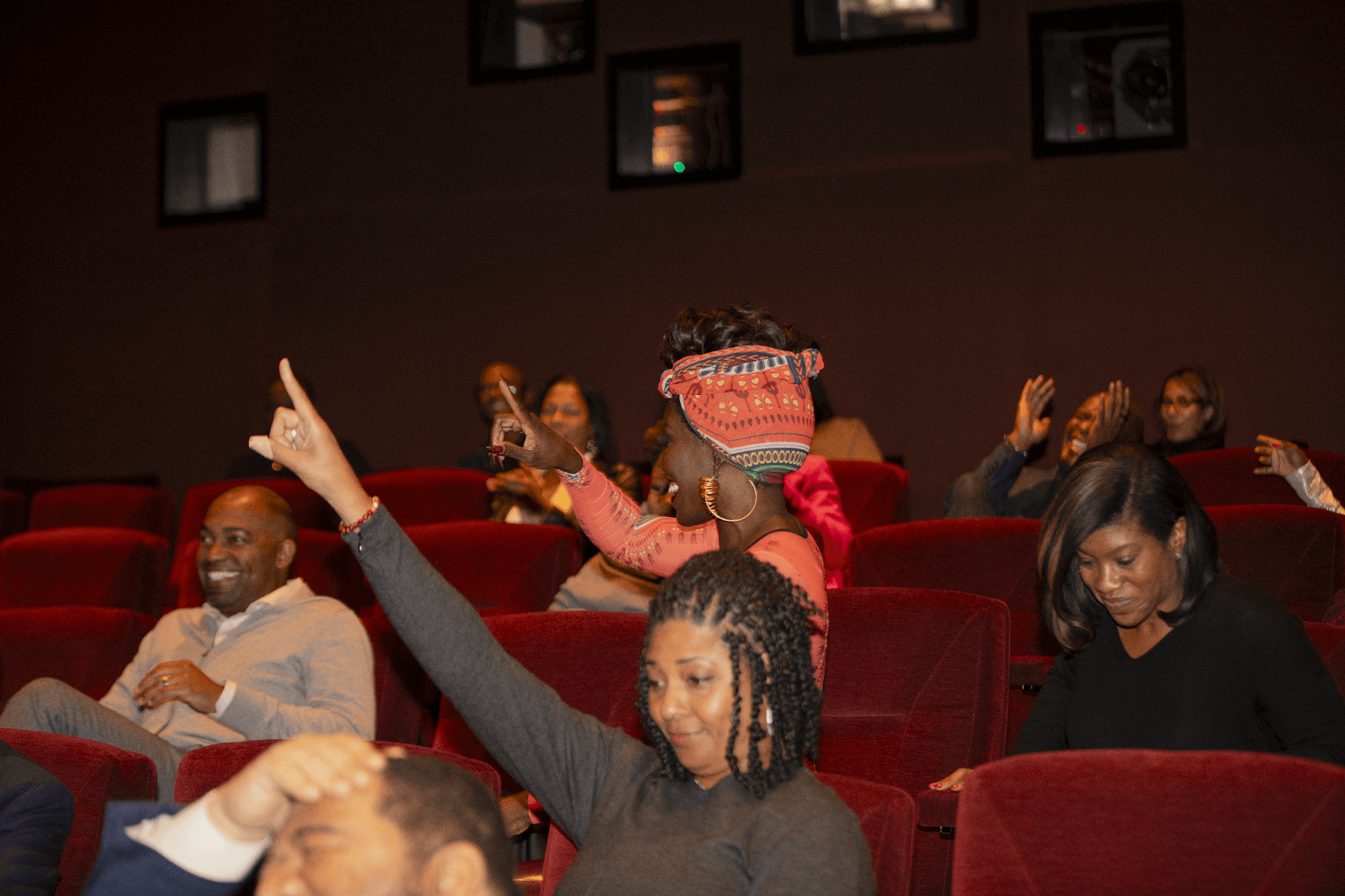 Audience members actively participating by raising their hands during the event, showing enthusiasm and engagement in the discussion.