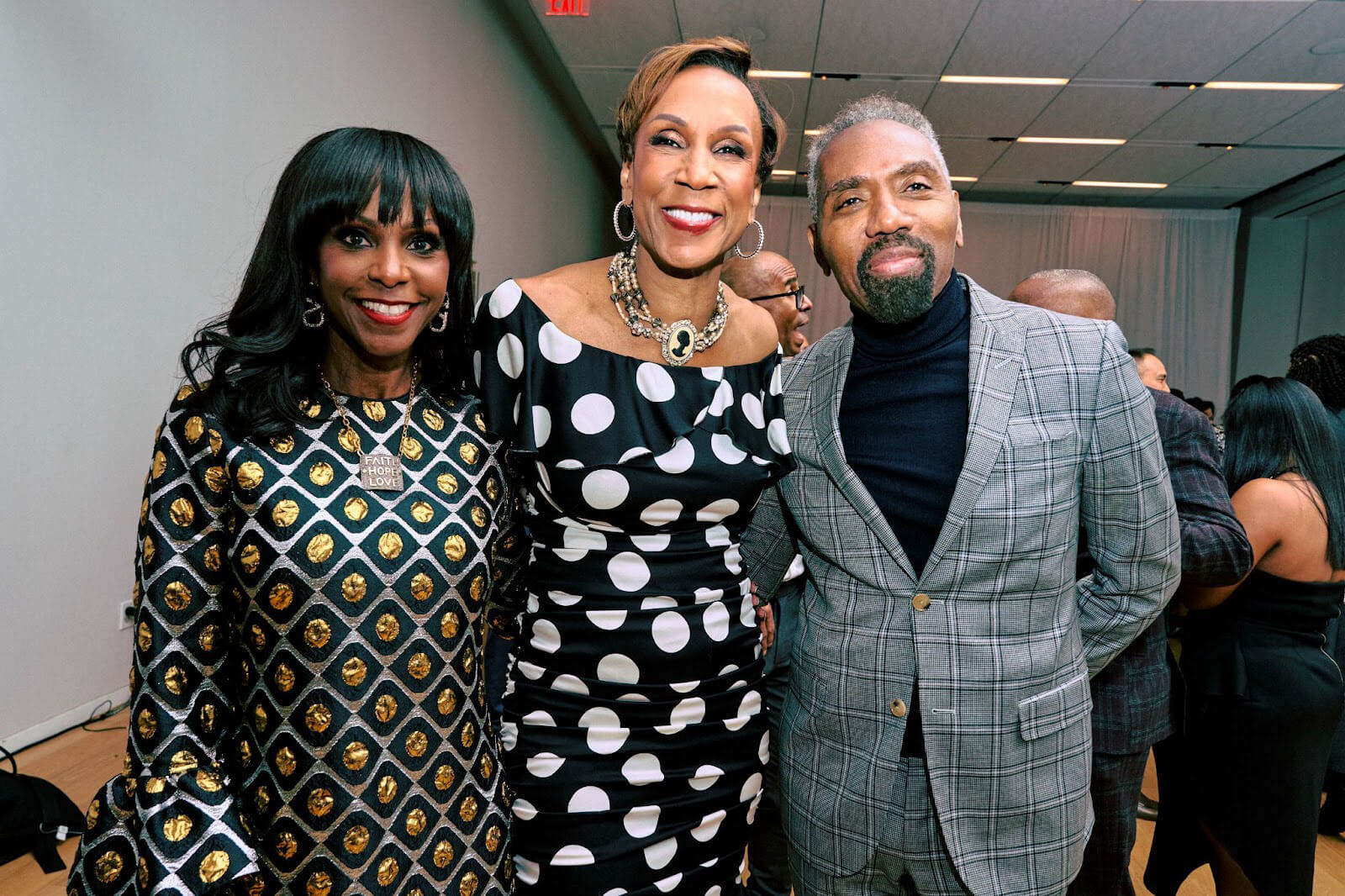 Three individuals posing together at an event, all dressed formally and smiling warmly.