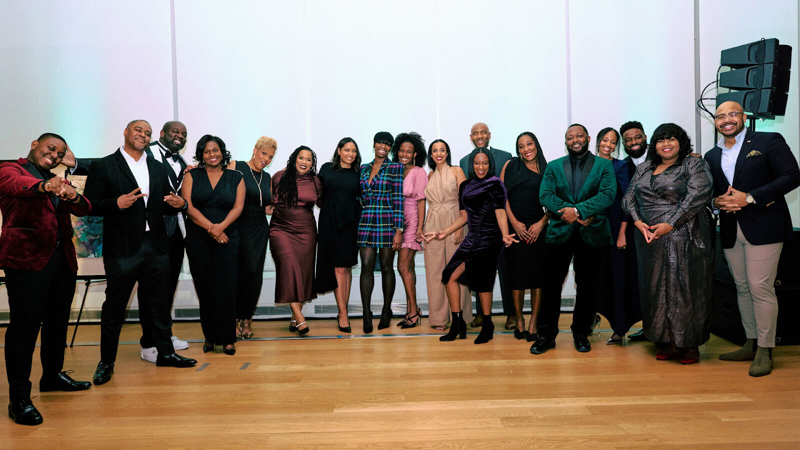 A large group photo of individuals dressed elegantly, standing together and posing during a formal event.