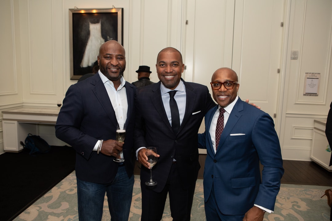 Three men wearing suits smiling.