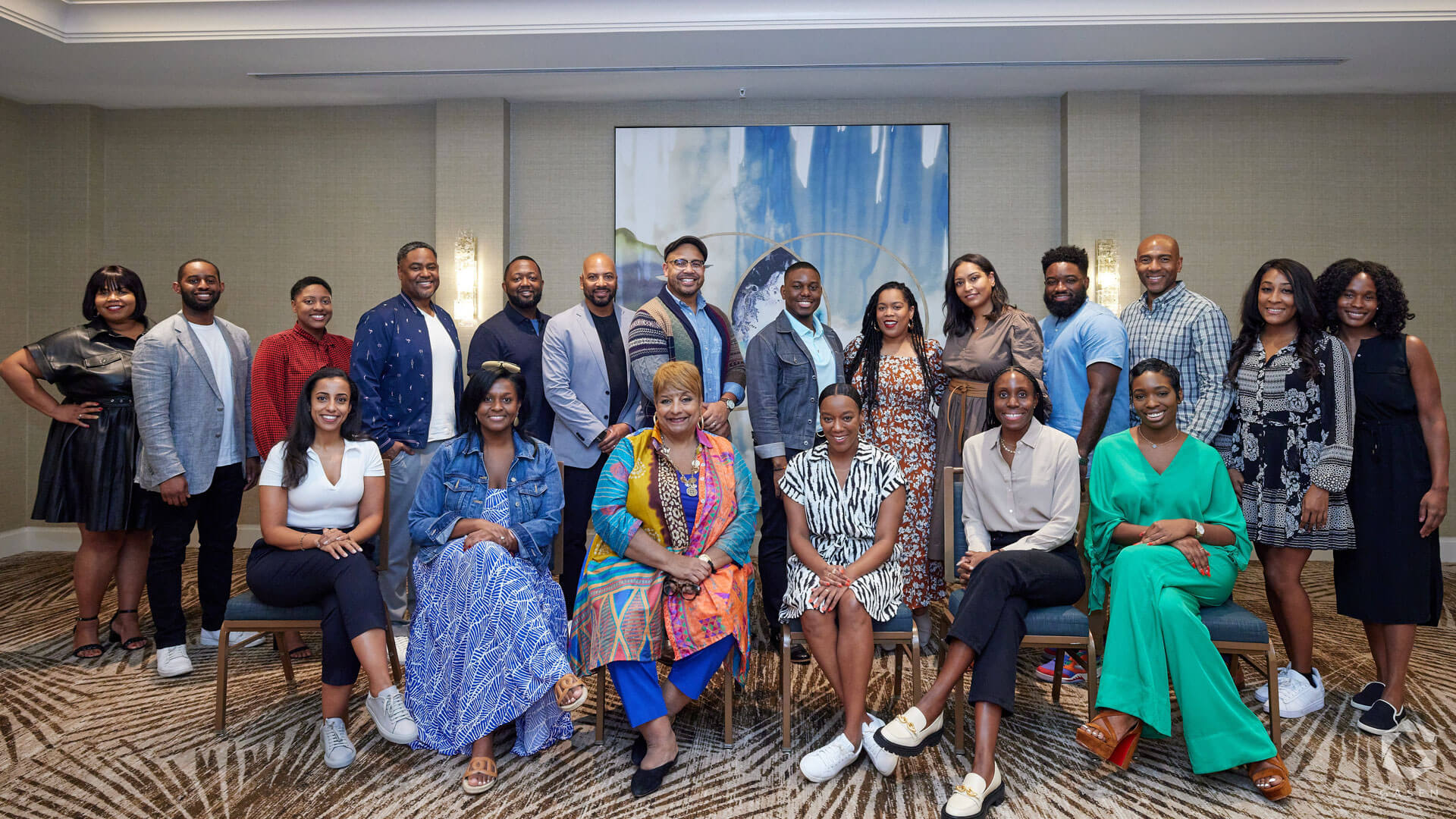 A diverse group of individuals posing together at an event, arranged in seated and standing rows, exuding camaraderie.