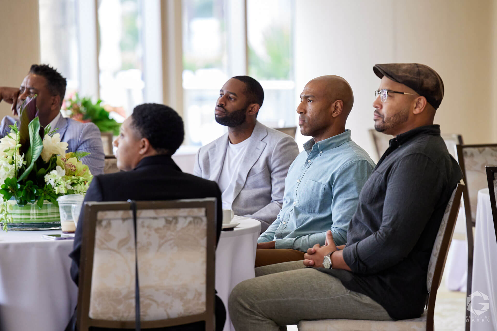 A group of men seated at a table, listening intently during a professional discussion.