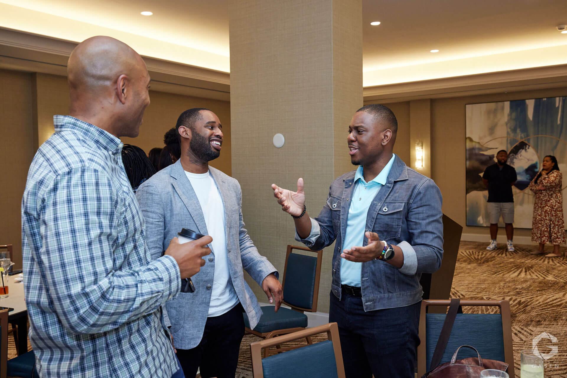 Three men standing together, engaged in a lively and friendly conversation during a professional event.