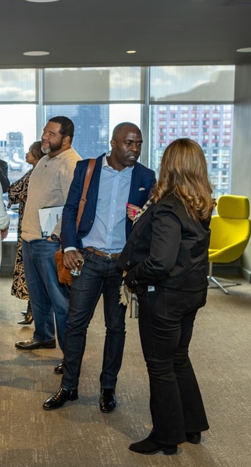 Man in blue blazer conversing with a woman in black during a professional gathering.