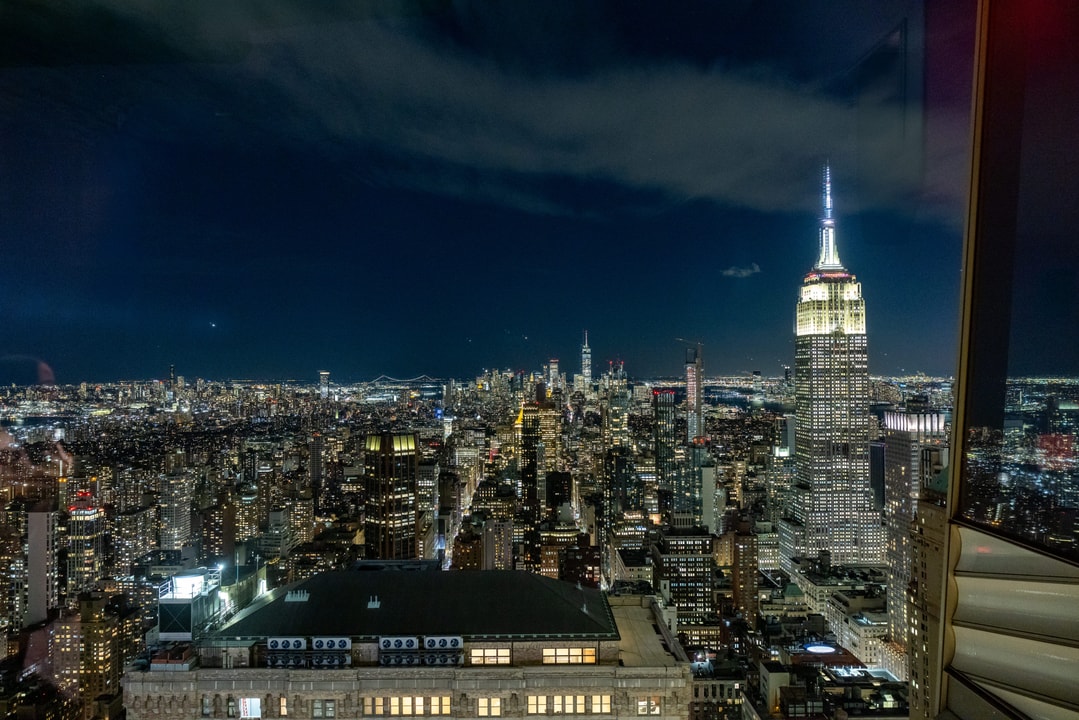 New York City Skyline at Night – A breathtaking aerial view of the New York City skyline at night, featuring the illuminated Empire State Building and distant bridges under a dark sky.