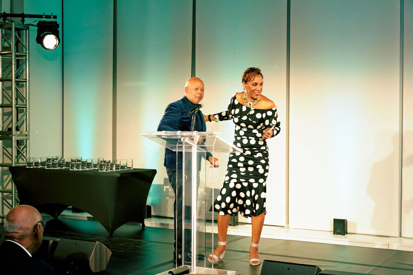 Two speakers on stage sharing a moment of laughter as they interact during the event.