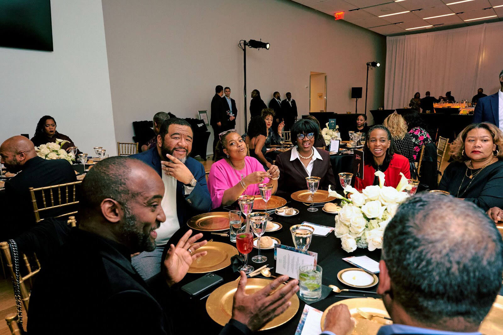 A group of guests seated at a round table enjoying lively conversation, with elegant table settings and decor.