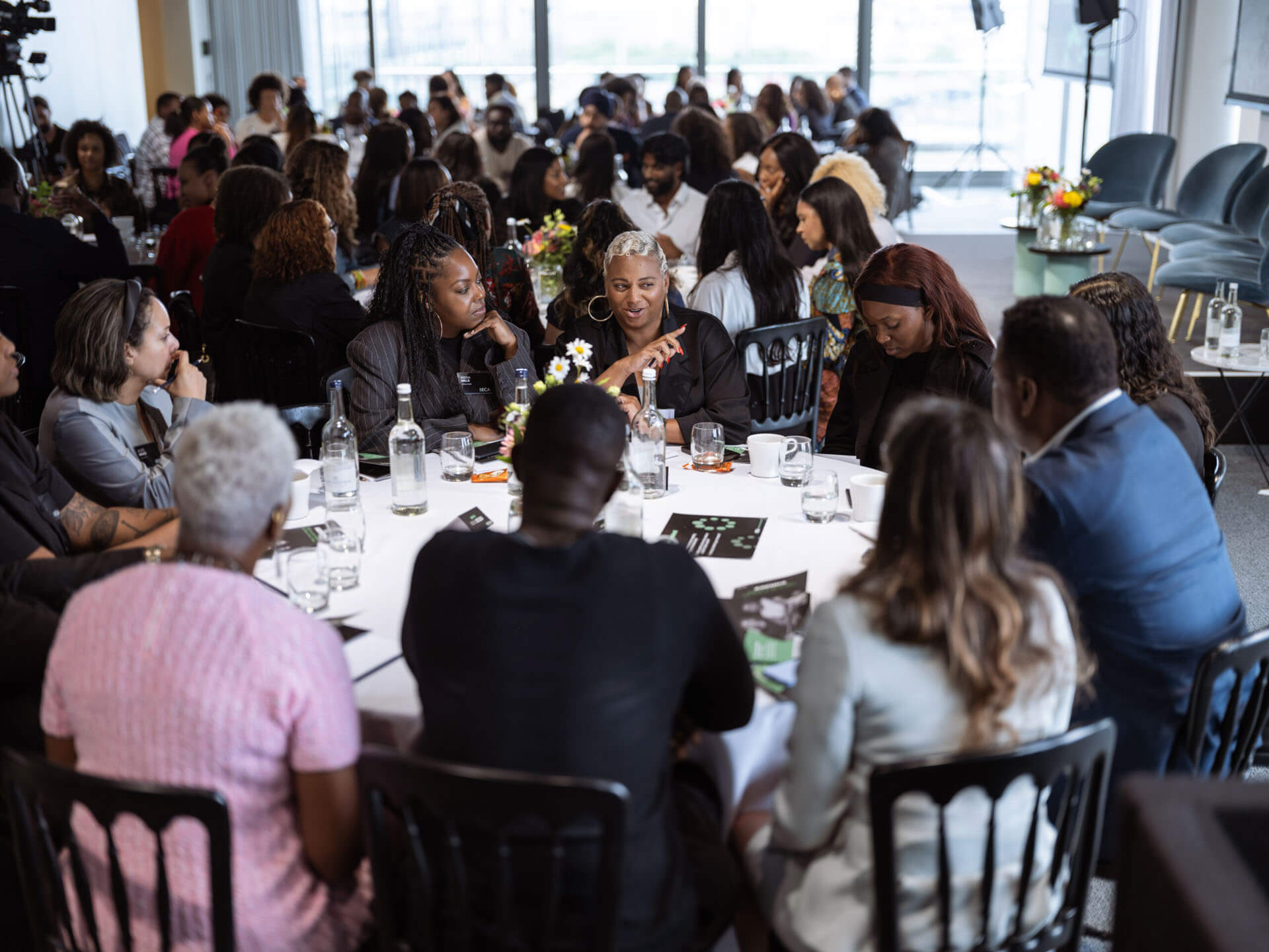Participants actively discussing topics around a round table, focusing on a conversation while surrounded by event materials.