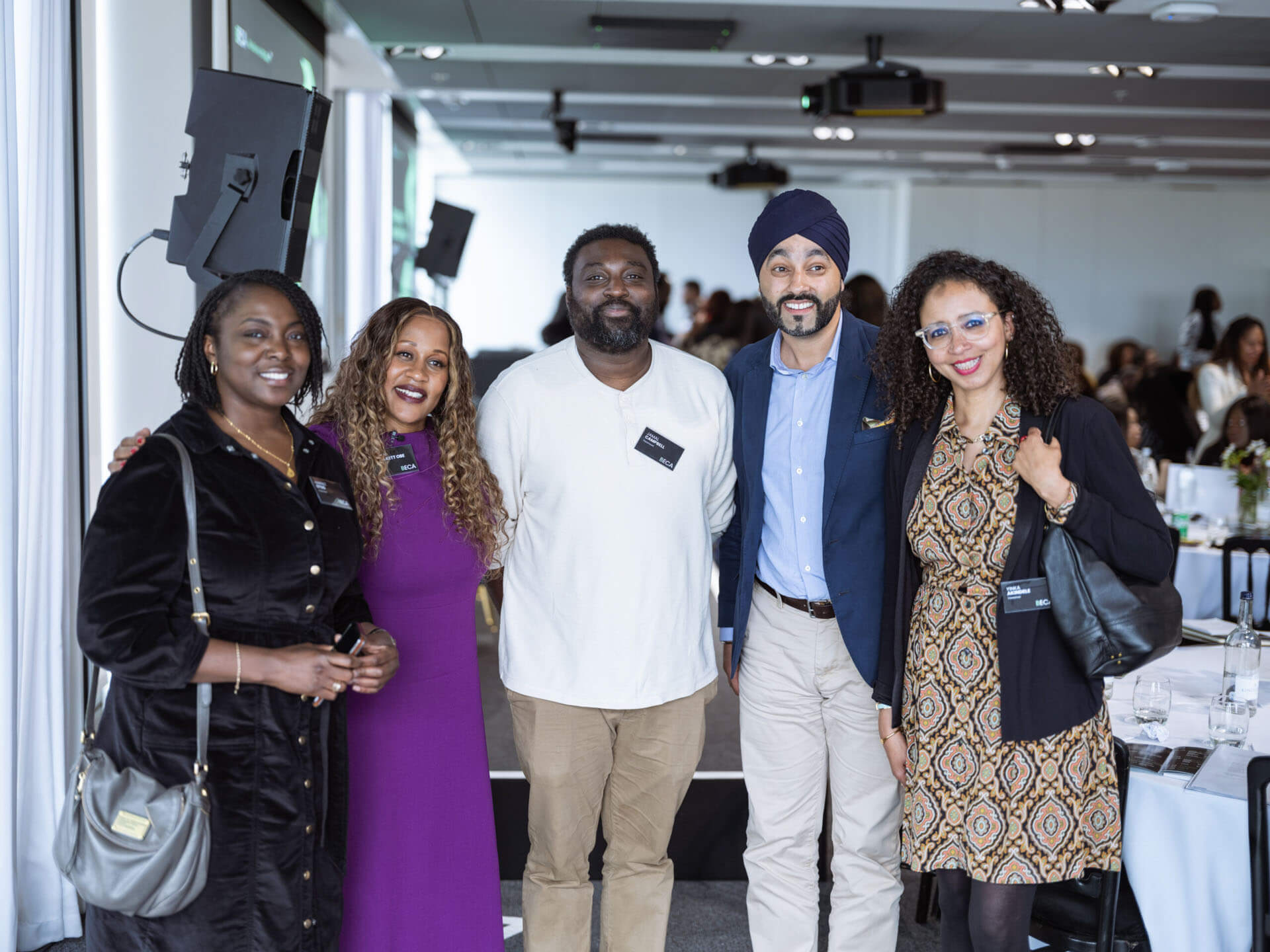 A group of five diverse attendees smiling and posing for a group photo at a professional gathering.