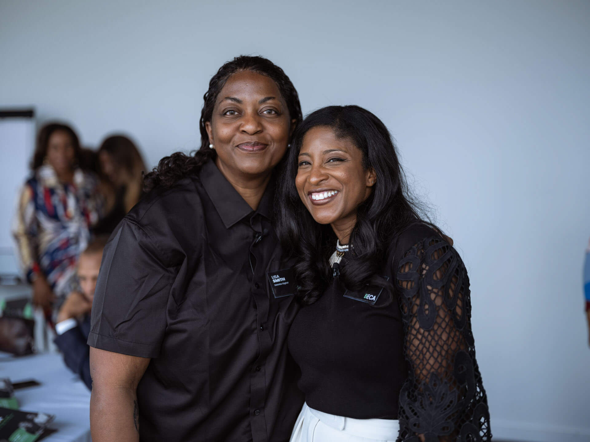 Two women posing and smiling for a photo at a professional event.