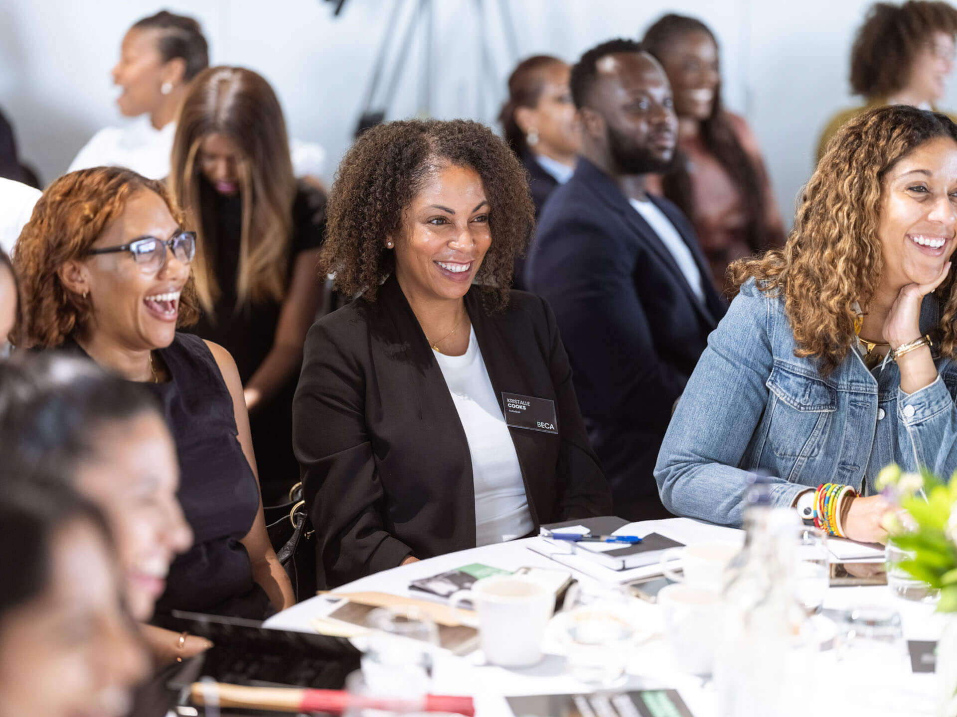 A table of attendees smiling and laughing during a conference session.