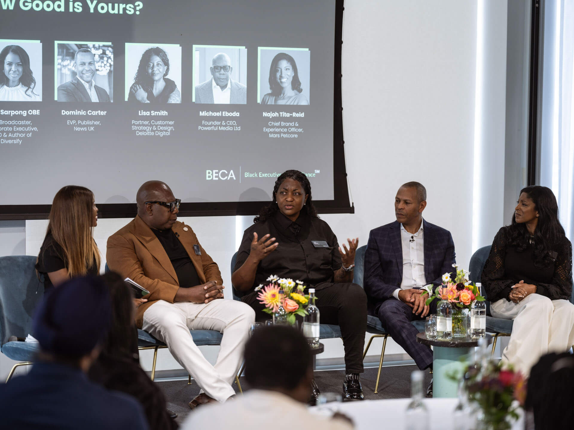 A panel discussion in progress with speakers seated on stage under a slide titled "How Good is Yours?"