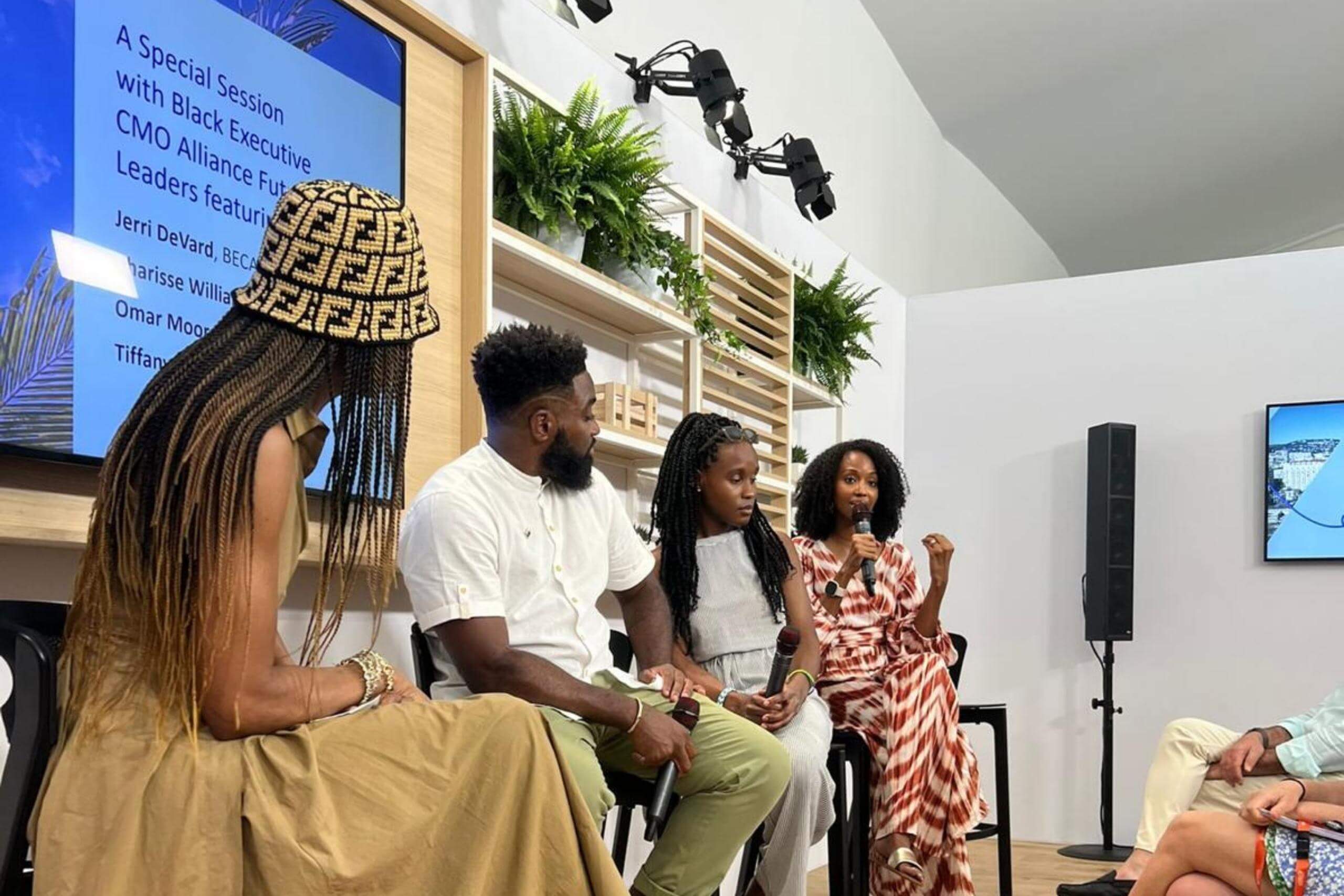 Another angle of the panel discussion, highlighting a different speaker who gestures while holding a microphone. The room has a professional setup with attentive participants.
