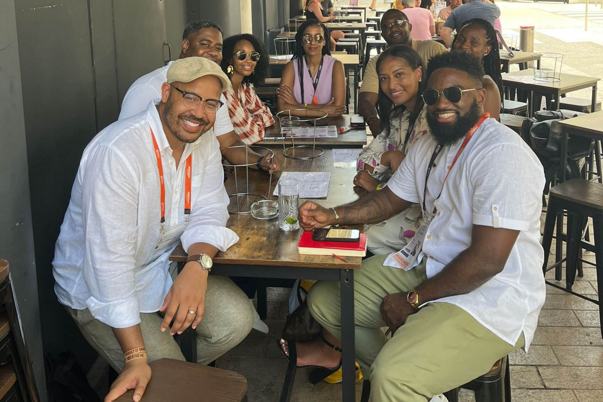 A group seated at an outdoor restaurant table, smiling and enjoying casual conversation.