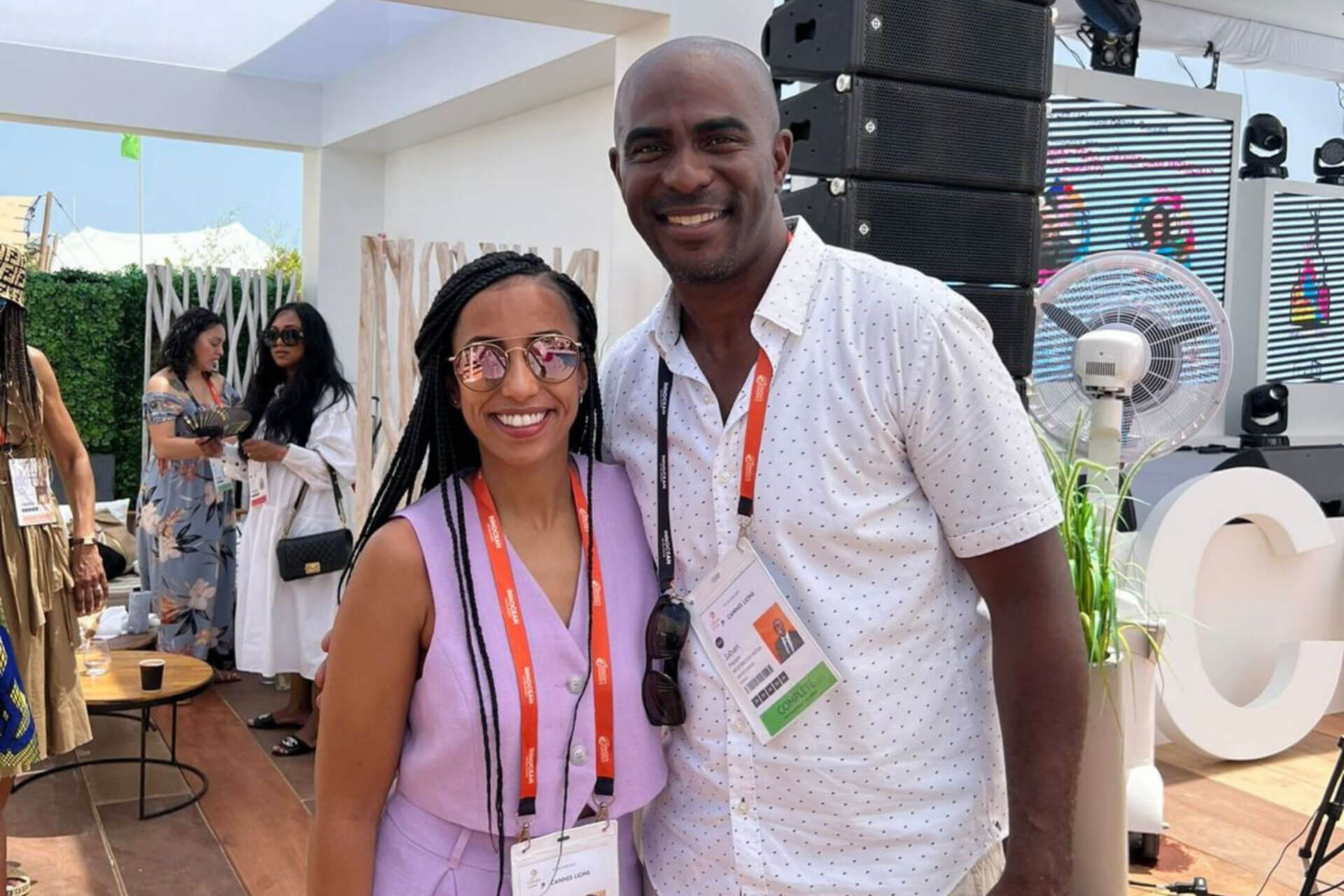 Two colleagues posing for a photo at an outdoor event, surrounded by a lively atmosphere.