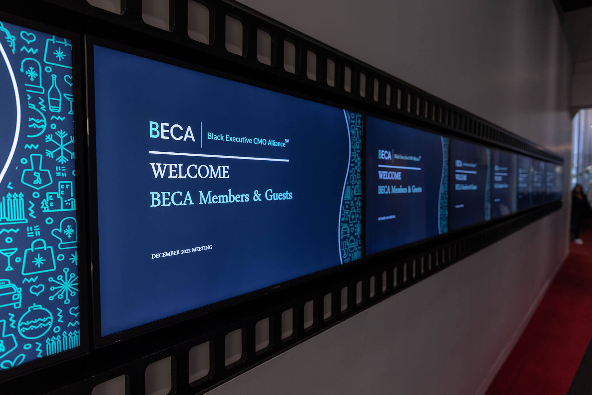 A digital screen wall displaying the welcome message "BECA Members & Guests" for a December 2022 meeting.