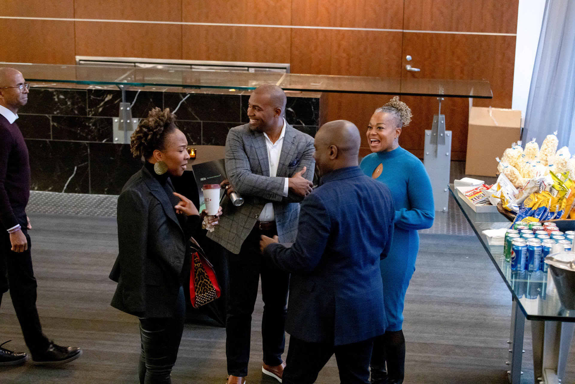 A group of attendees gathered at a snack bar, engaged in conversation and sharing laughter.