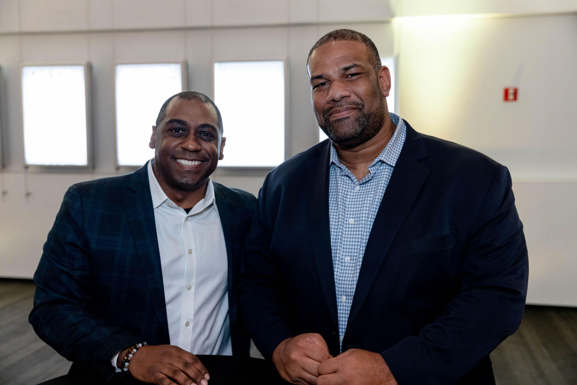 Two men, both smiling, pose for a photo together in a modern event space.