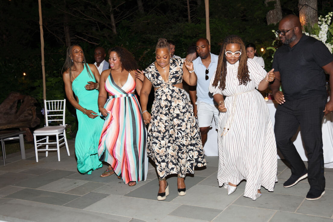 Guests dancing energetically on a patio during an evening gathering. Everyone is smiling and enjoying the lively atmosphere.