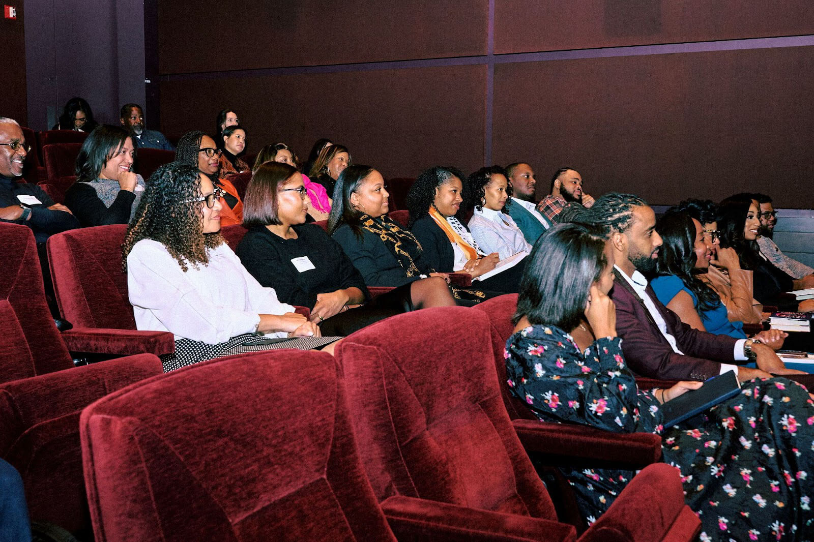 A large group of attendees seated in a theater-style setting, listening attentively to a presentation or speaker during an event.