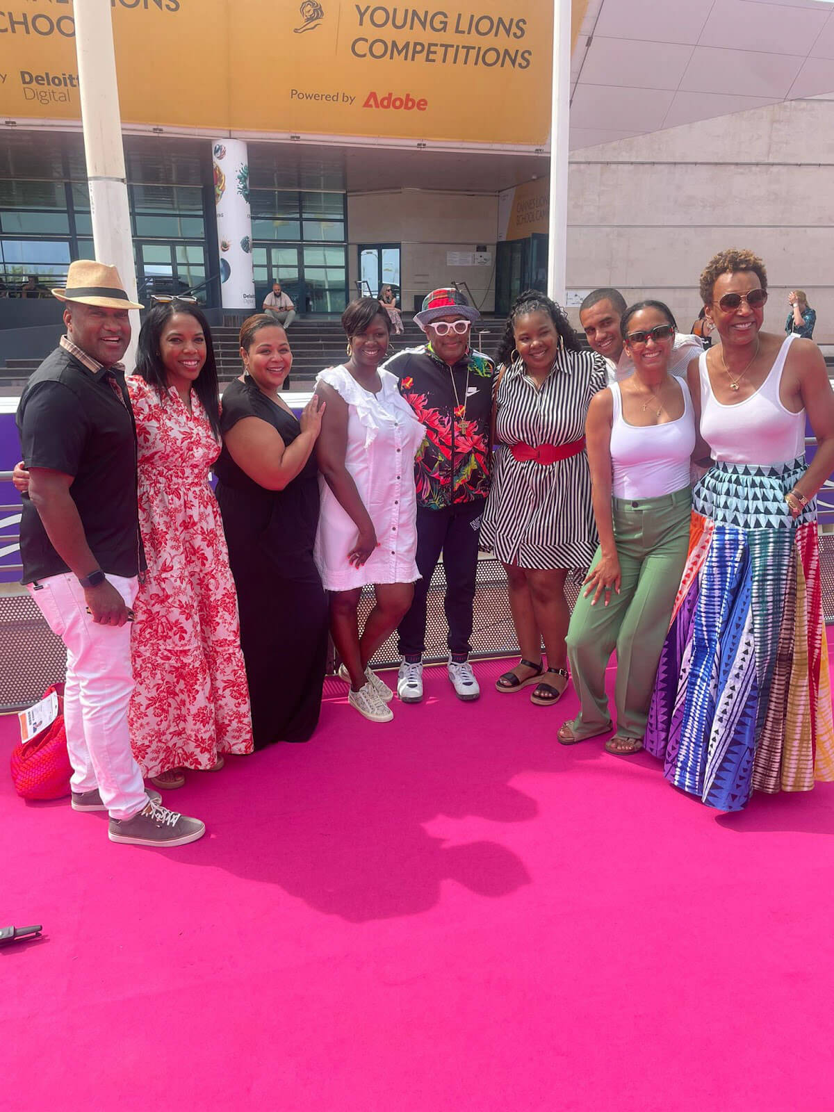 A group of people posing on a pink carpet outside a venue, with "Young Lions Competitions" signage visible above.