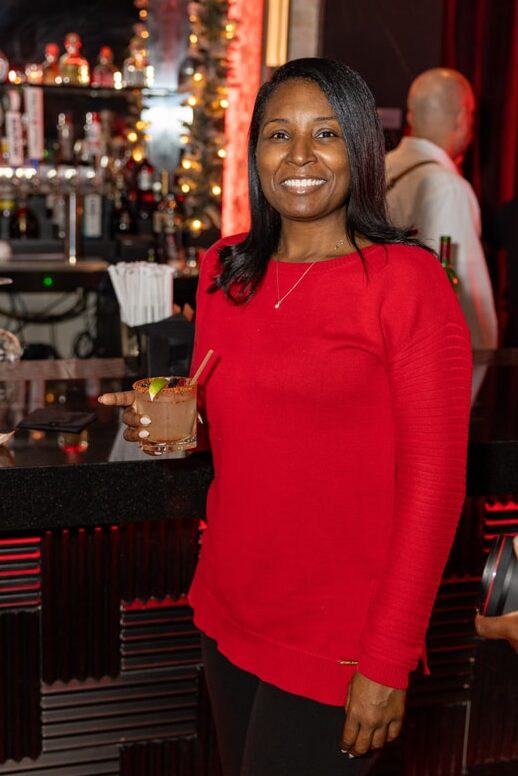 A woman in a red sweater smiles whle holding a margarita at the Brooklyn Chophouse.