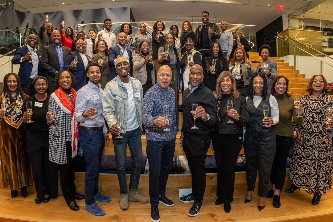 A group photo of the BECA Members, Future Leaders and V-Suite participants toasting towards the camera.