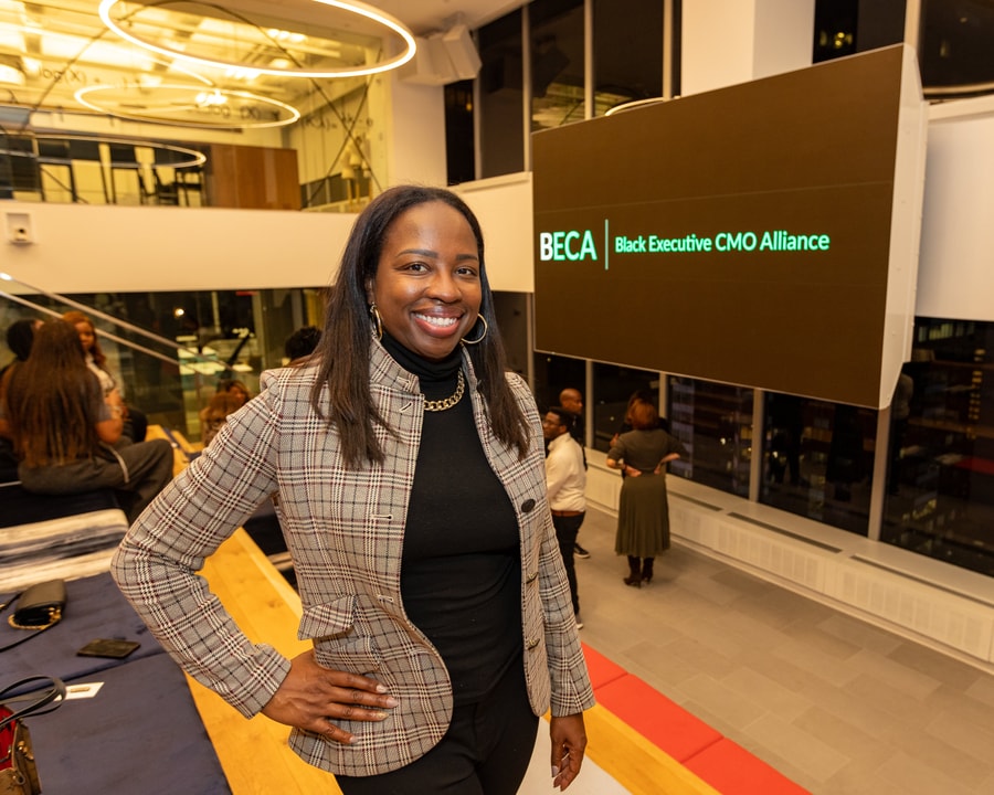 A BECA Playbook participant smiles in front of the BECA logo at Paramount Global HQ in NYC.