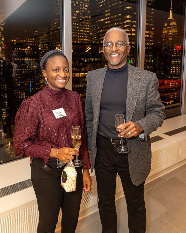 BECA Members socializing with a night scene of New York City in the background.