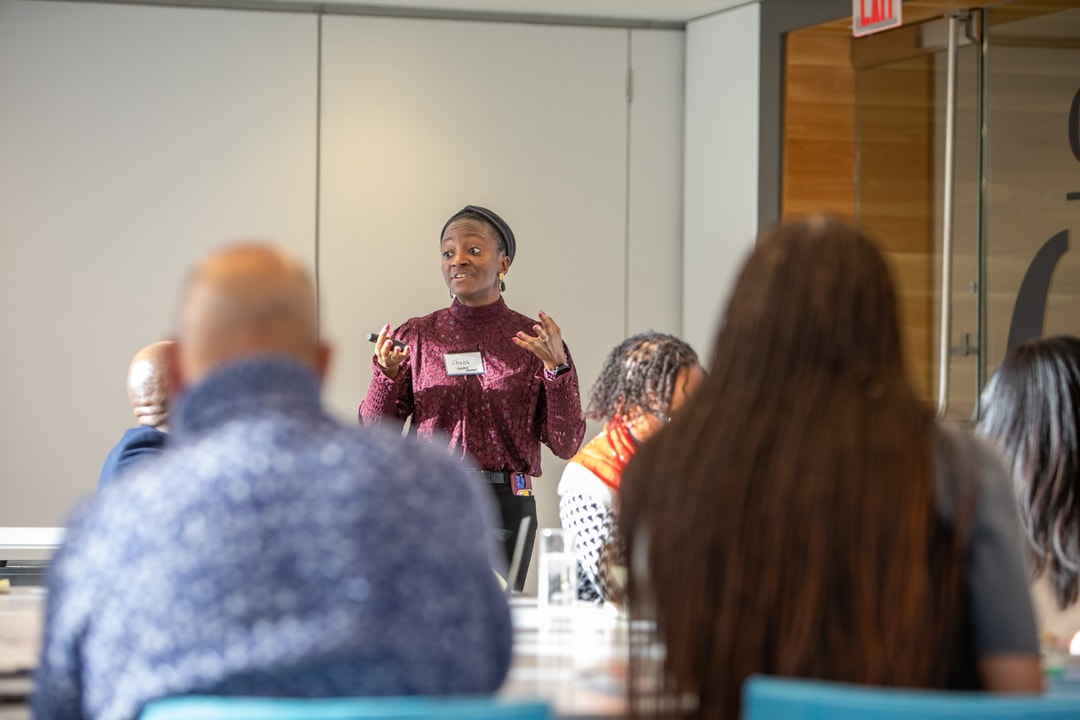 A BECA V-Suite particpant in a maroon blouse gesticulates while talking.