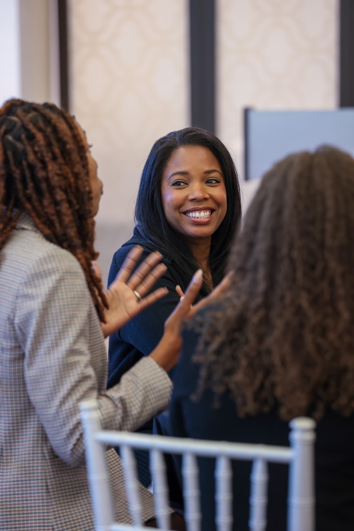 A BECA Future Leader smiles as she listens to her colleague's animated discussion.